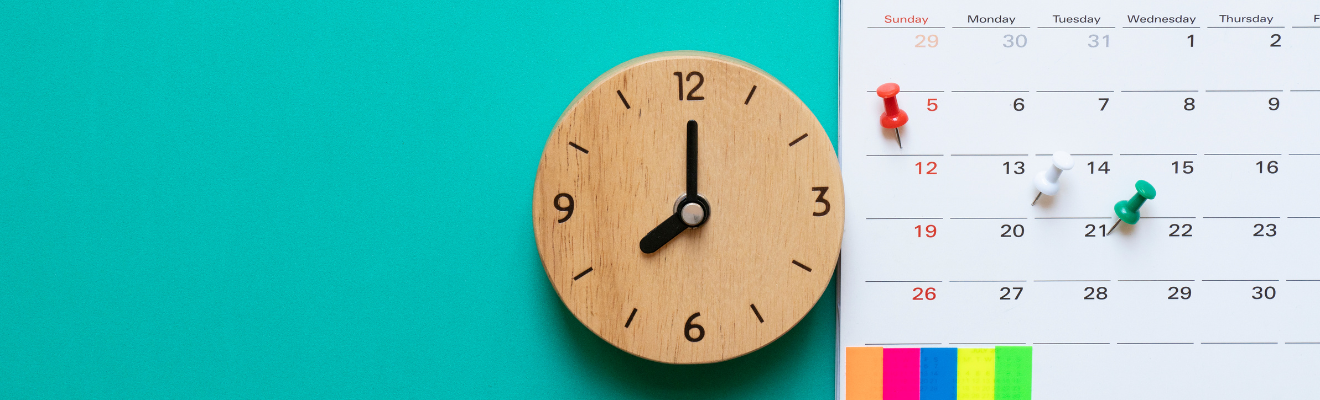 orologio di legno su fondo azzurro e calendario con puntine colorate