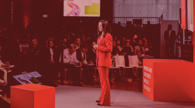 donna vestita di rosso che fa uno speech su un palco