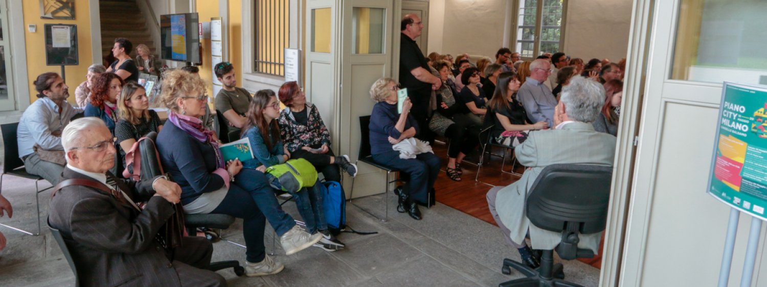 persone sedute in sala per uno spettacolo musicale insieme ad altre persone che sono seduto nell'atrio