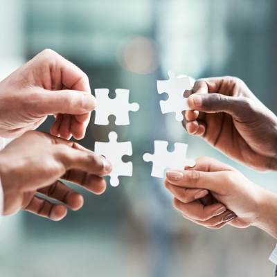 mani di uomini e donne con in mano un pezzo di puzzle