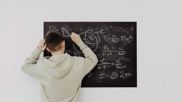 ragazzo scrive alla lavagna formule matematiche