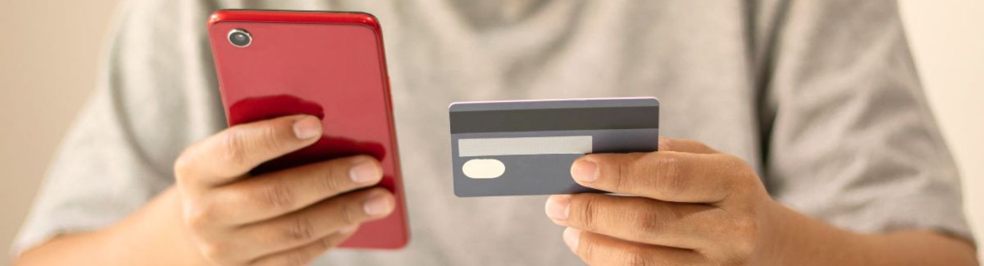 giovane che tiene in mano una carta di credito e uno smartphone